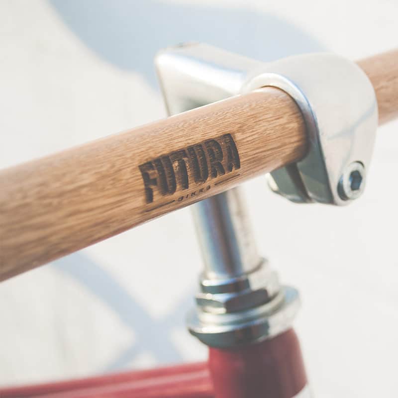 Wooden bicycle handlebar with metal clamp.