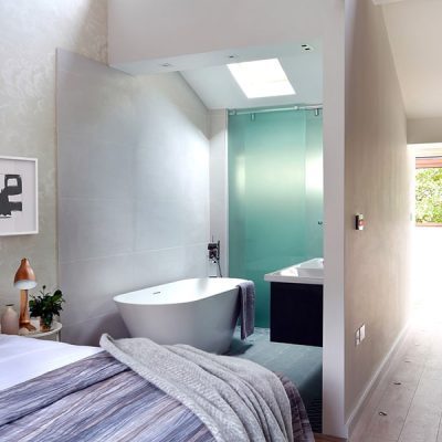 Modern bedroom with bathtub and skylight.