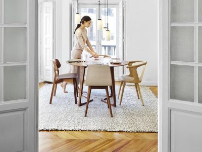 Woman setting table in modern dining room.