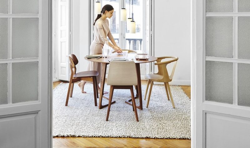 Woman setting table in modern dining room.