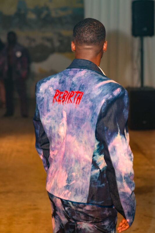 Model wearing colorful jacket with "Rebirth" text.