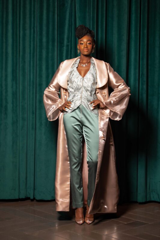 Person in stylish outfit against green curtain.
