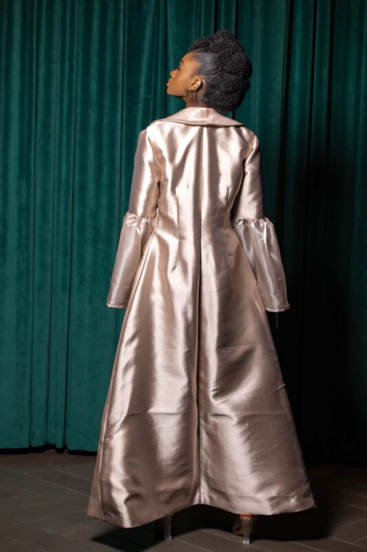Woman wearing elegant satin gown, back view.