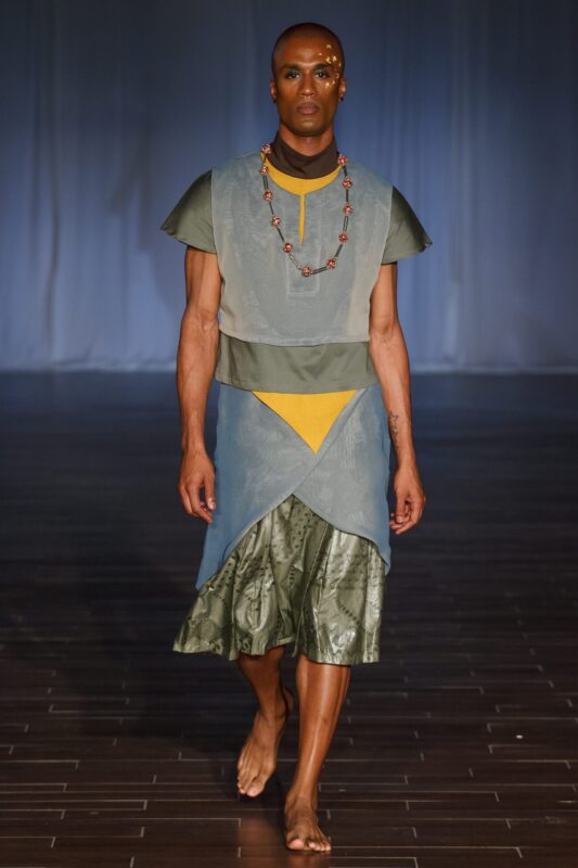 Model walking in layered outfit on runway.