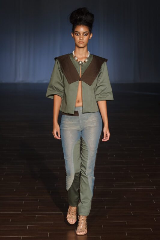 Model walking in stylish green outfit.