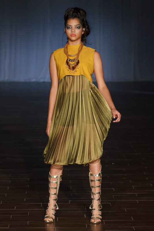 Model in yellow dress on runway.