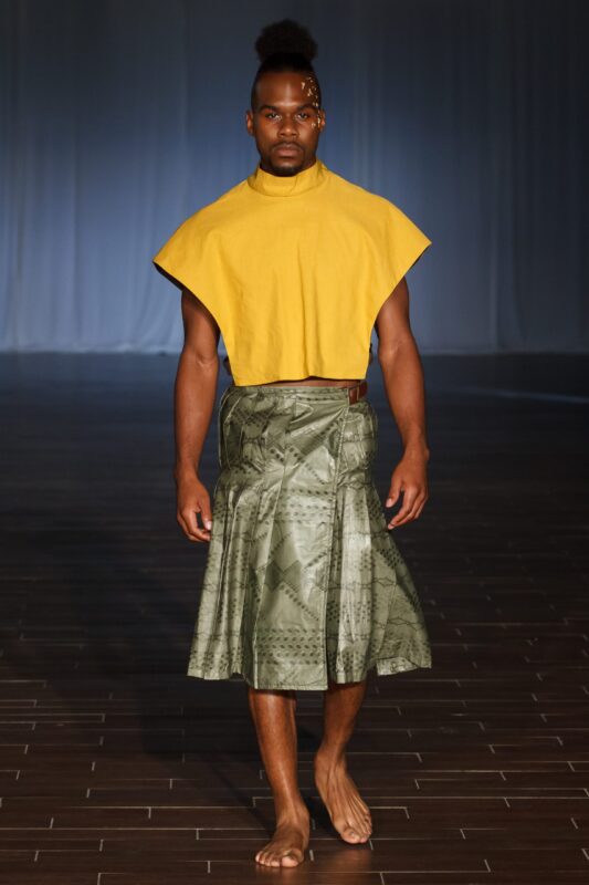 Model in yellow top and green skirt.
