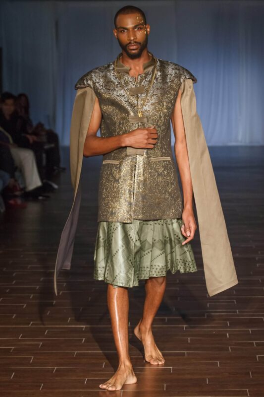 Model walking in metallic outfit on runway.