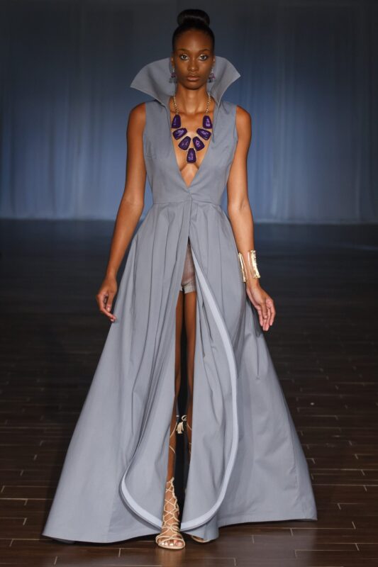 Model wearing elegant gray gown on runway.