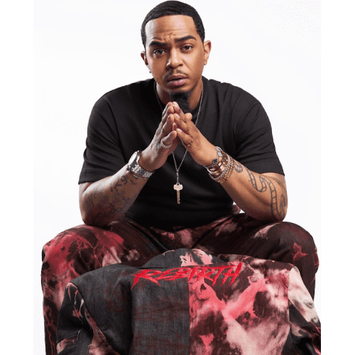 Man sitting, hands clasped, wearing patterned pants.