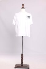 White T-shirt on a wooden mannequin stand.