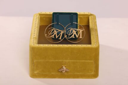 Gold earrings on yellow jewelry box.