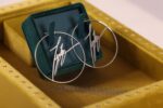 Silver hoop earrings in yellow jewelry box.
