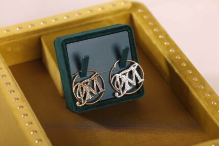 Gold hoop earrings with initials in box.