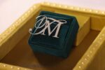 Silver "M" on green velvet jewelry box.