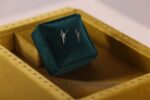 Silver earrings on green velvet display box.
