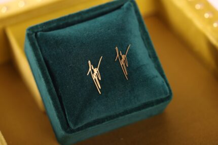 Gold earrings on teal velvet display.