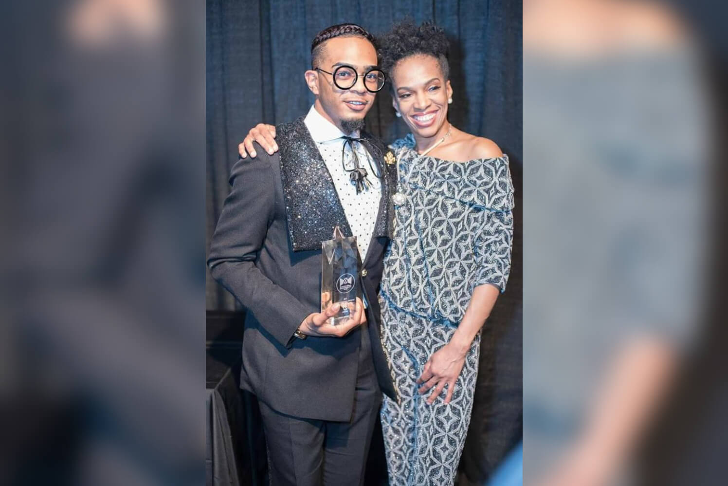 Two people posing with an award trophy.
