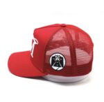 Red mesh trucker cap with white logo and emblem.